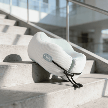 CHOOKLY ergonomic memory foam travel neck pillow on modern concrete steps, premium airplane travel pillow designed for neck support and comfortable sleep during flights